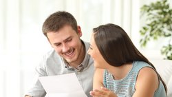 Ein Mann und eine Frau lachen sich an und halten ein Blatt in der Hand