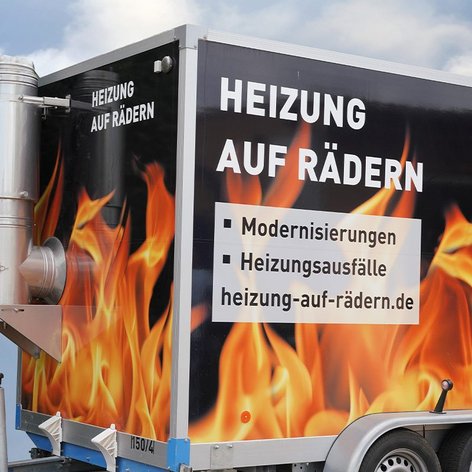 Ein mobiler Heizungsanhänger mit auffälligem Flammendesign und Informationen zu Heizungsmodernisierungen.