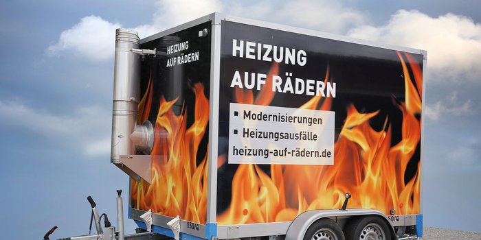 Ein mobiler Heizungsanhänger mit auffälligem Flammendesign und Informationen zu Heizungsmodernisierungen.